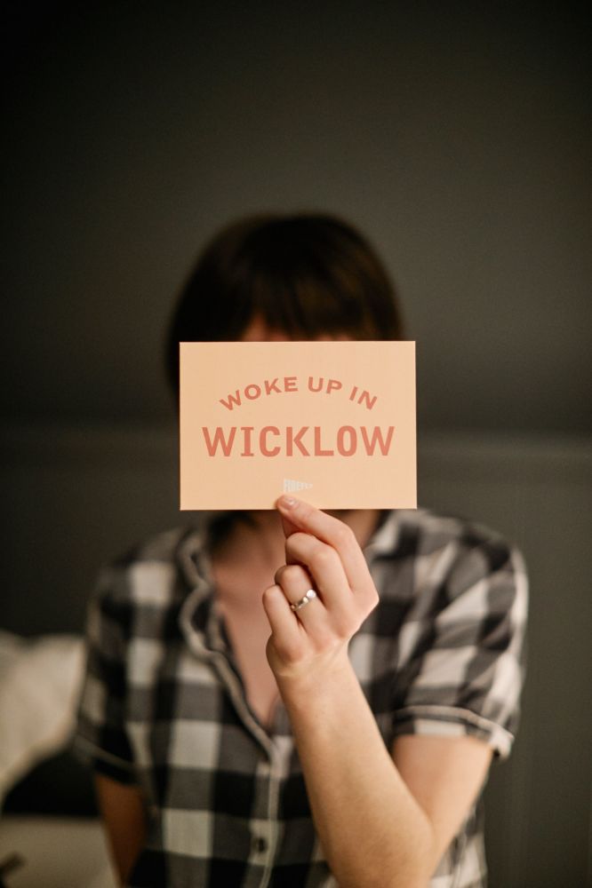 Hotelgast hält die Postkarte „Wake up in Wicklow“ in der Hand