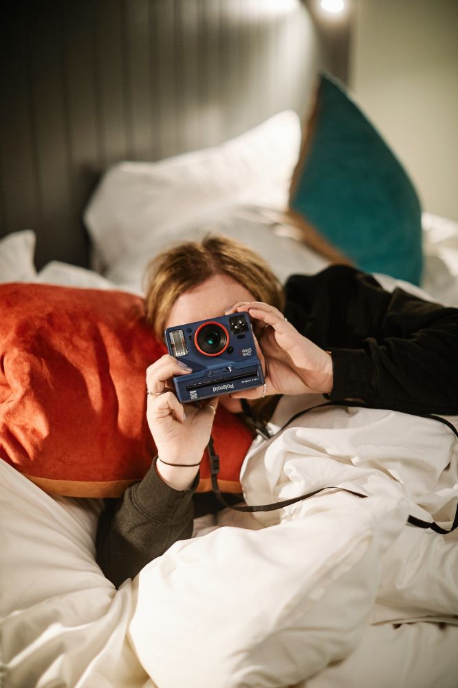 Hotel guest laying on double bed with camera