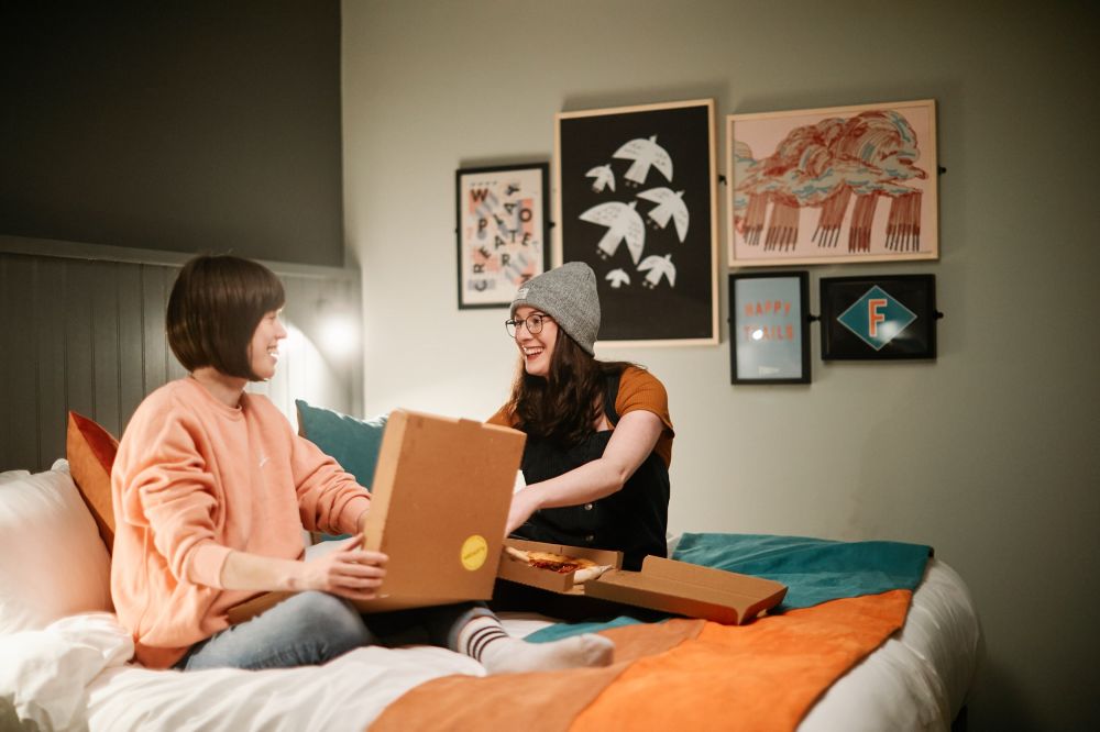 Guests eating pizza on hotel double bed