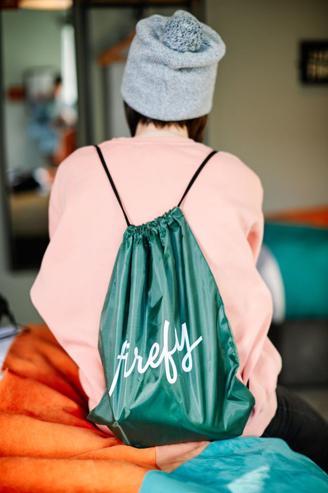 Guest sitting on hotel bed wearing Firefly bag