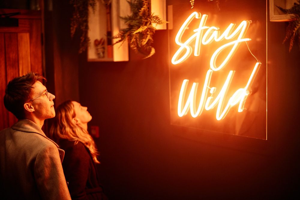 Hotel guests in entry hallway looking at neon sign